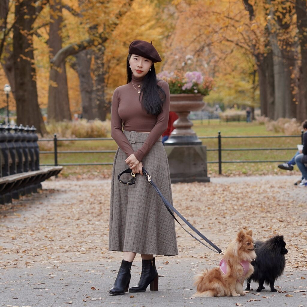 Vivian R Tang poses in dark academia fashion in Central Park New York City NYC with her pomeranians against a fall setting