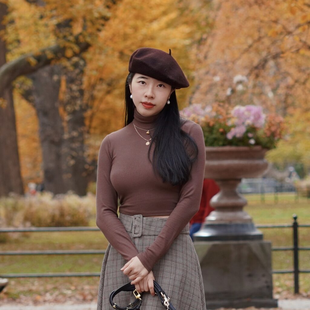 Vivian R Tang poses in dark academia fashion in Central Park New York City NYC with her pomeranians against a fall setting